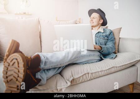 Il giovane uomo d'affari in cappello sta sognando circa il commercio, il successo ed i soldi. Concetto di incuria, partenza, vacanza di viaggio Foto Stock