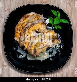 bistecche alla griglia con formaggio e cipolle su piatto nero Foto Stock