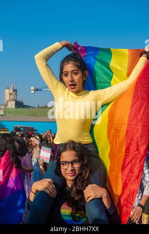 Mumbai / India 01 Febbraio 2020 ragazza indiana della comunità LGBT seduta sulle spalle di un'altra ragazza e ondeggiante bandiera di colore arcobaleno durante parad orgoglio Foto Stock