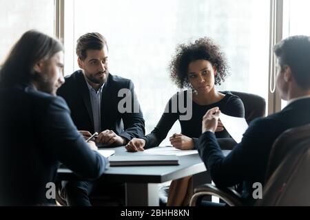 Partner aziendali seri e diversi che discutono della strategia di progetto durante la riunione Foto Stock