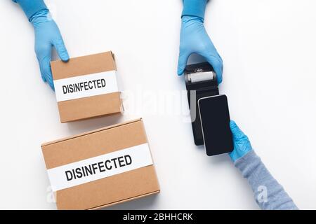 Uomo che paga con il cellulare per la consegna rapida disinfettata Foto Stock