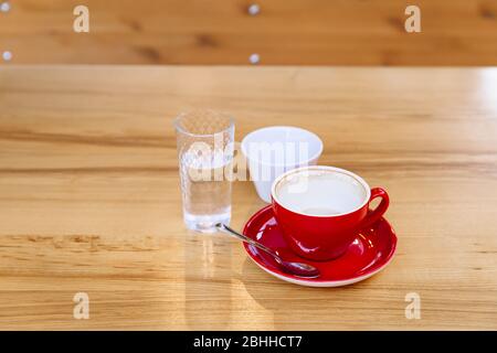 Tazze da caffè sporche, cappuccino e un bicchiere d'acqua si trovano su un tavolo di legno. Pausa caffè. Deliziatevi con gusto e aroma. Foto Stock