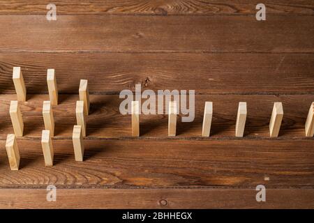 File di domino in piedi su tavolo di legno Foto Stock