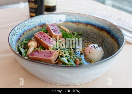 Filetto di tonno alla griglia su insalata di piselli verdi in piatto di argilla fatto a mano Foto Stock