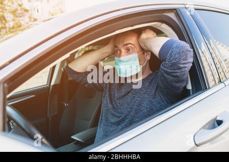 Uomo che indossa la maschera protettiva per evitare l'infezione di virus e l'aria inquinata che si diffonde all'interno della sua auto. Assistenza sanitaria, coronavirus, influenza Foto Stock