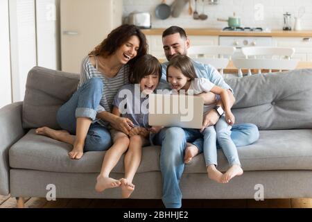 I bambini si divertono guardando video divertenti sul computer con i genitori. Foto Stock