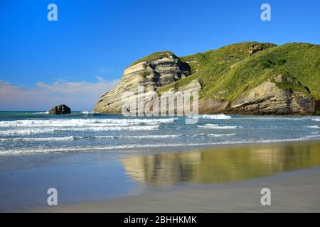 Bellissimo paesaggio neozelandese alla spiaggia di Wharariki con rocce, oceano, onde e un riflesso. Isola del Sud. Foto Stock