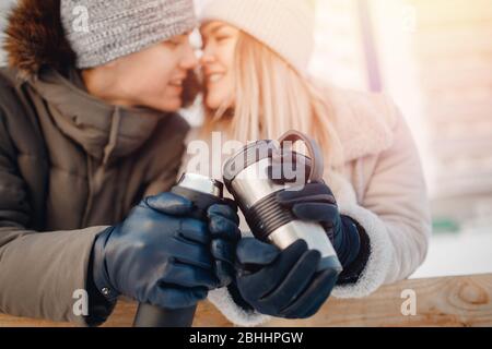 Amorevole coppia bevande calde tè o caffè da tazze thermos sulla strada invernale in pista di ghiaccio Foto Stock