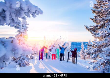 Squadra felice di snowboarder e sciatore che si divertono a sgombrare la neve. Sole leggero nella foresta invernale alba Foto Stock