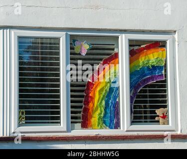 Windsor, Berkshire. 26 aprile 2020. Un grazioso arcobaleno è esposto in una finestra della casa insieme a un orso di teddy del bambino che porta la positività e la speranza durante il blocco Pandemic di Coronavirus. Credit: Maureen McLean/Alamy Live News Foto Stock