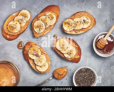 panino con burro di arachidi e banana su fondo grigio in cemento. vista dall'alto Foto Stock