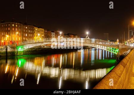 Città di Dublino in Irlanda, ha Penny Bridge di notte sul fiume Liffey con riflessi in acqua Foto Stock