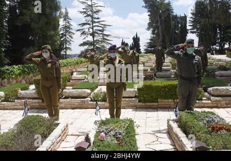 Gerusalemme, Israele. 26 aprile 2020. I soldati israeliani indossano maschere per la protezione contro il coronavirus, mentre salutano le tombe dei soldati caduti, prima del Memorial Day, nel Monte Herzl Cimitero militare, Domenica 26 aprile, a Gerusalemme. Alle famiglie ereaved sarà proibito visitare il cimitero nel giorno commemorativo di Israele per i soldati caduti e le vittime del terrore, che inizia al tramonto, il 27 aprile, nel tentativo di fermare la diffusione del COVID-19. Foto di Debbie Hill/UPI Credit: UPI/Alamy Live News Foto Stock