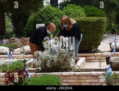 Gerusalemme, Israele. 26 aprile 2020. Gli israeliani indossano una maschera per proteggersi dal coronavirus, mentre visitano la tomba di un soldato caduto, prima del Memorial Day, nel Monte Herzl Cimitero militare, Domenica 26 aprile, a Gerusalemme. Alle famiglie ereaved sarà proibito visitare il cimitero nel giorno commemorativo di Israele per i soldati caduti e le vittime del terrore, che inizia al tramonto, il 27 aprile, nel tentativo di fermare la diffusione del COVID-19. Foto di Debbie Hill/UPI Credit: UPI/Alamy Live News Foto Stock