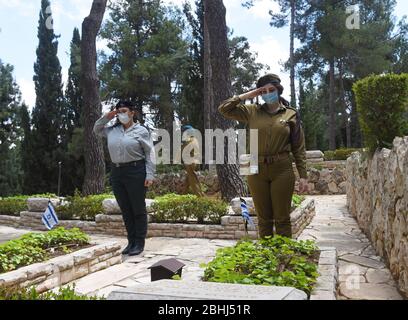 Gerusalemme, Israele. 26 aprile 2020. I soldati israeliani indossano una maschera per la protezione contro il coronavirus, mentre salutano le tombe dei soldati caduti, prima del Memorial Day, nel Monte Herzl Cimitero militare, Domenica 26 aprile, a Gerusalemme. Alle famiglie ereaved sarà proibito visitare il cimitero nel giorno commemorativo di Israele per i soldati caduti e le vittime del terrore, che inizia al tramonto, il 27 aprile, nel tentativo di fermare la diffusione del COVID-19. Foto di Debbie Hill/UPI Credit: UPI/Alamy Live News Foto Stock