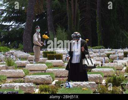 Gerusalemme, Israele. 26 aprile 2020. Un israeliano detiene una bandiera nazionale e fiori presso la tomba di un soldato caduto, prima del Memorial Day, nel Monte Herzl Cimitero militare, Domenica 26 aprile, a Gerusalemme. Alle famiglie ereaved sarà proibito visitare il cimitero nel giorno commemorativo di Israele per i soldati caduti e le vittime del terrore, che inizia al tramonto, il 27 aprile, nel tentativo di fermare la diffusione del COVID-19. Foto di Debbie Hill/UPI Credit: UPI/Alamy Live News Foto Stock