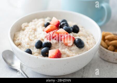 Prima colazione porridge farinata d'avena con fragola, mirtillo in ciotola bianca, vista Closeup di pasto sano prima colazione Foto Stock