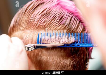 Vista posteriore delle mani del parrucchiere sono taglio donna capelli corti, primo piano. Foto Stock