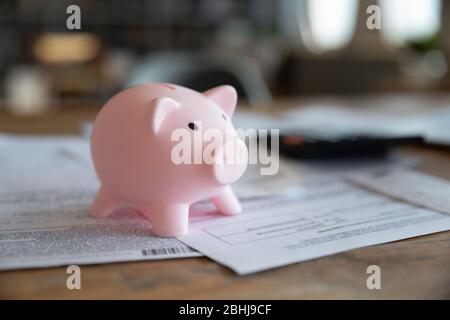 Chiudi la banca rosa piggy su scrivania in legno con le fatture Foto Stock