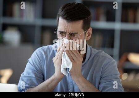 Primo piano uomo d'affari malsano che soffia naso corrente, utilizzando tovagliolo Foto Stock