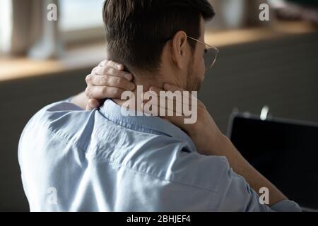 Primo piano giovane uomo stanco massaggiante i muscoli rigidi del collo Foto Stock
