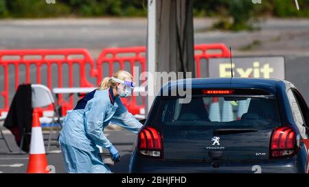 Watford, Regno Unito. 26 aprile 2020. Un lavoratore in dispositivi di protezione individuale (PPE) parla con un conducente di auto in un centro di test che ha aperto il 23 aprile nel parcheggio del Watford General Hospital. I soggetti idonei a utilizzare il centro di test sono i membri del personale ospedaliero o la loro famiglia che sono sintomatici del Covid 19. Per accelerare il programma di test verso un obiettivo di 100,000 test al giorno entro il 30 aprile stabilito da Matt Hancock, Segretario della Sanità, negli ultimi giorni sono stati allestiti molti altri centri di test, compresi i centri di test mobili a comparsa. Credit: Stephen Chung / Alamy Live News Foto Stock