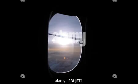 luminoso disco solare su un ampio orizzonte sotto la vista dell'ala dell'aereo dall'oblò scuro della cabina passeggeri del liner Foto Stock