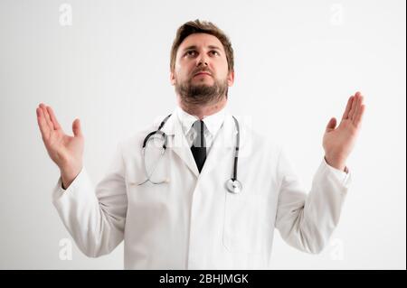 Ritratto di medico maschile con stetoscopio in uniforme medica con braccia aperte che guardano in posa su un fondo bianco isolato Foto Stock