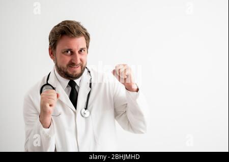 Ritratto di medico maschile con stetoscopio in uniforme medica ha sollevato pugni esclamando con gioia ed eccitazione posando su un bianco isolato sfondo Foto Stock