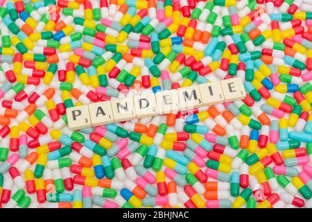 Pillole multicolori capplets & lettere piastrelle: Pandemie - tedesco, francese, e olandese & ceco (Noun) parola per Pandemic. CV19 / Coronavirus concettuale. Foto Stock