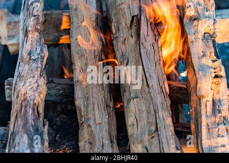 Una foto closeup all'aperto di fuoco ardente e fuoco di legna da ardere in un fuoco con fuoco rosso e arancio fuoco brillante e braci Foto Stock