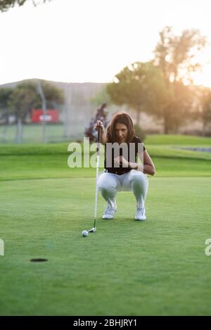 Donna golfer controllare la linea per mettere la sfera di golf sul verde Foto Stock