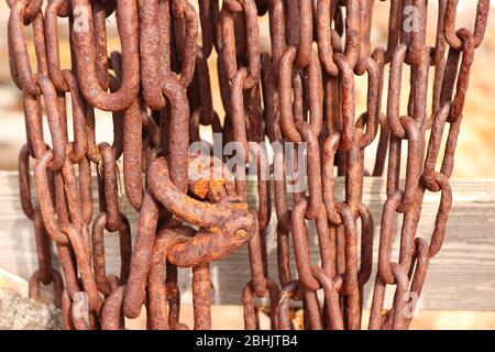 Catena arrugginita appesa su una recinzione di legno in campagna Foto Stock