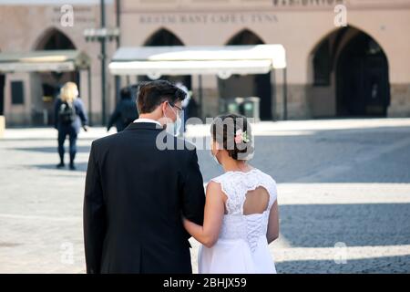 Praga, Repubblica Ceca - 23 aprile 2020: Coppia di nozze in maschere mediche viso nella città vecchia. Matrimonio durante la pandemia coronavirus. COVID-19 matrimoni. Foto orizzontale. Foto Stock