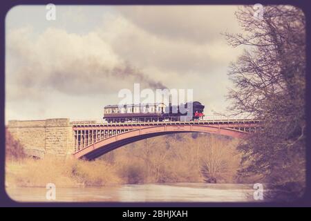Vista laterale di una locomotiva a vapore d'epoca britannica e di una carrozza ferroviaria che attraversa il Victoria Bridge sul fiume Severn, la linea ferroviaria patrimonio della Severn Valley. Foto Stock