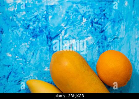 Frutta di arancia. Papaya, mango e arancione isolato su sfondo blu. Vista dall'alto. Spazio di copia. Disposizione piatta. Cibo, frutta tropicale esotica, concetto di viaggio. Foto Stock
