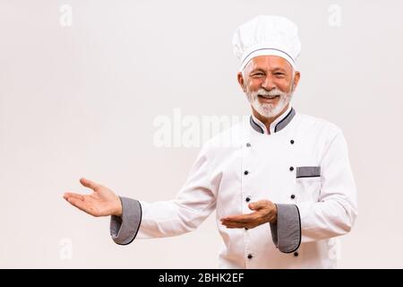 Ritratto dello chef senior che mostra il gesto di benvenuto. Foto Stock