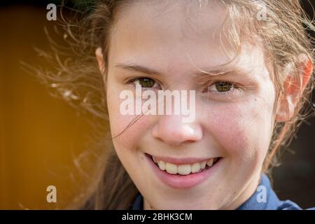Un ritratto di una giovane giovane giovane giovane giovane, sorridente in un ambiente naturale soleggiato Foto Stock
