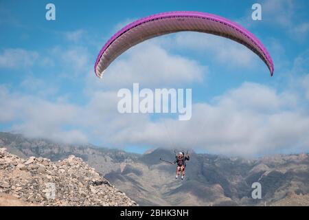 Parapendio con istruttore pilota in tandem nel cielo sopra le montagne sulla Costa Adeje, Tenerife Foto Stock