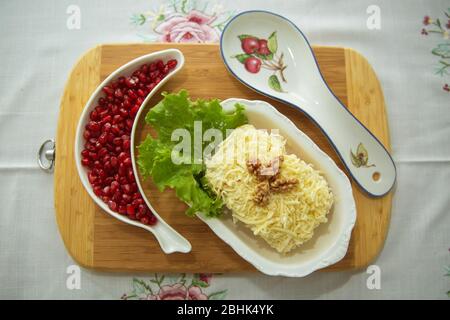 Insalata tradizionale russa Mimoza. Isolato su sfondo di legno. Vista dall'alto. INSALATA DI POLLO con noci e funghi . Melograno granulato Foto Stock