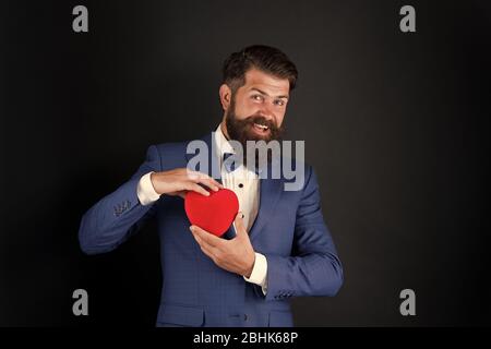 Posso aiutarla. Giornata mondiale del cuore. Brutale hipster barbuto in abito formale. Uomo d'affari in cravatta di prua. Assistenza sanitaria. Decorazione di giorno di San Valentino. Tuxedo uomo con cuore rosso. Festa di festa. Concetto di amore. Foto Stock