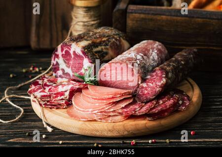 prelibatezze di carne su sfondo di legno, salsiccia secca su un tagliere Foto Stock