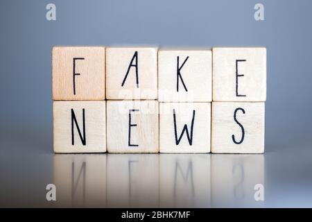 Cubess di legno con le parole Fake News su sfondo grigio, Fake News concetto social media Foto Stock