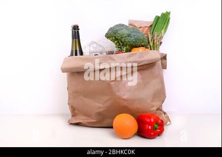 Set di cibo su sfondo bianco. Sacchetto di carta con scorte alimentari scorte di cibo di crisi per il periodo di isolamento di quarantena. Consegna di cibo, donazione, coronavirus.verdure fresche, frutta, olio d'oliva. Messa a fuoco morbida. Foto Stock