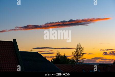 East Lothian, Scozia, Regno Unito. 26 aprile 2020. UK Weather: Strana formazione di nuvola arancione allungata al tramonto sui tetti della casa al tramonto, ma annuncia un altro bel giorno domani Foto Stock