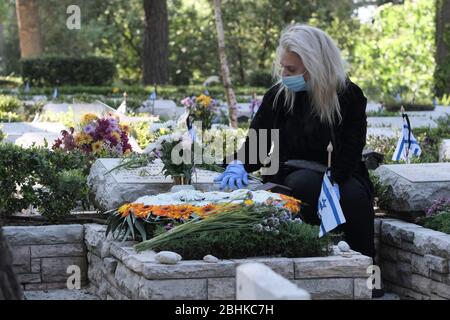 Gerusalemme, Israele. 26 Apr 2020. Una donna israeliana che indossa una maschera protettiva a causa del coronavirus COVID-19 si lamenta della tomba di un amato presso l'esercito nazionale del Monte Herzl a Gerusalemme, mentre Israele si prepara a celebrare il giorno del memoriale per i soldati caduti. Le cerimonie ufficiali non si svolgeranno quest'anno a causa di un coprifuoco nazionale per combattere la pandemia COVID-19. Foto Stock