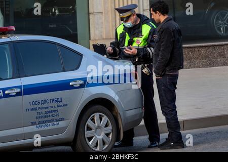 Mosca, Russia. 26 aprile 2020. Polizia stradale in maschera facciale controlla il codice di pass digitale del conducente durante la pandemia del romanzo coronavirus malattia COVID-19. Il 13 aprile 2020, il governo di Mosca ha introdotto un sistema di permessi digitali volto a limitare ulteriormente la circolazione. Nell'ambito del nuovo regime, divenuto obbligatorio dal 15 aprile, è necessario richiedere i permessi per viaggiare su un veicolo o sui mezzi pubblici per la città Foto Stock