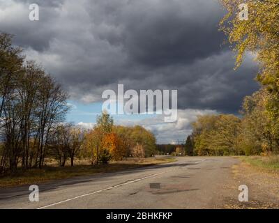 Strada vuota nella zona di esclusione di Chernobyl. Cielo drammatico. Foto Stock