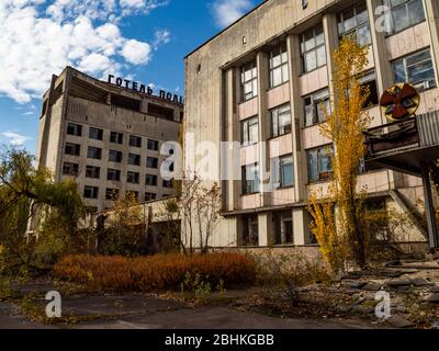 Hotel Polissia in abbandonata città fantasma Pripyat. Iscrizione sul tetto - Hotel Polissya. Di fronte una parte di casa di festa con il segno di radioattività Foto Stock