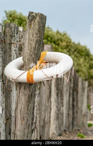 Lifebuoy appeso ad un palo sulla spiaggia di Youghal, Irlanda Foto Stock